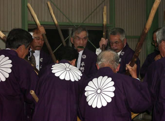 口々に榊の葉をくわえて餅つきをする様子